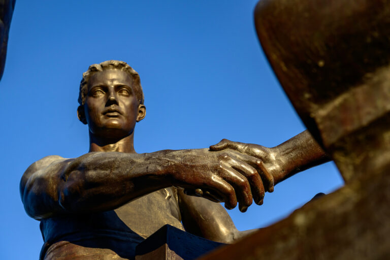 The two figures that stand beside Alma Mater represent "Learning" and "Labor" after the university's motto "Learning and Labor" shake hands to signify their collaborative effort. Alma Mater, who watches out over the campus of the University of Illinois Urbana-Champaign.