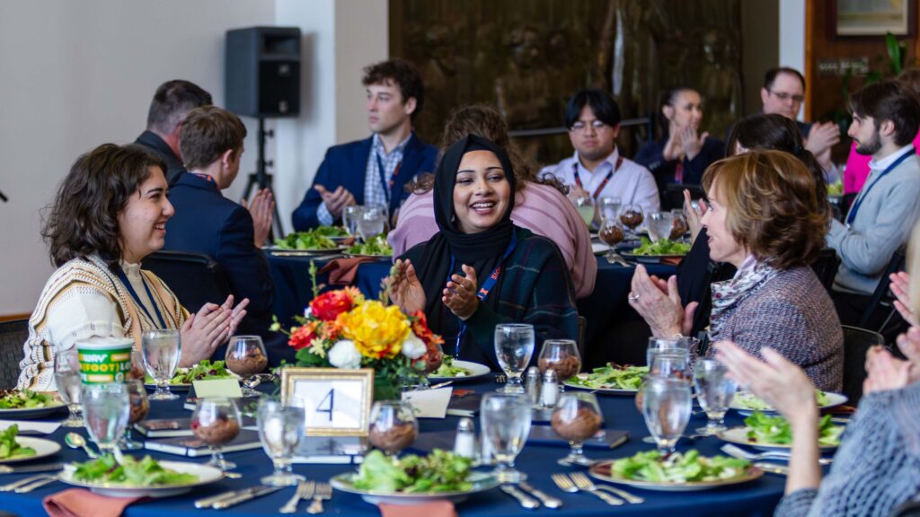 Students and alumni sit at a table during a meal in the College of Law pavilion