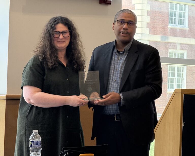 Arden Rowell accepts scholarly excellence award from Jamelle Sharpe