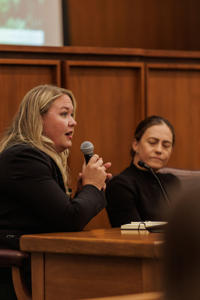 A woman holds a microphone and speaks during the AI in Cancer Surgery and Care Conference