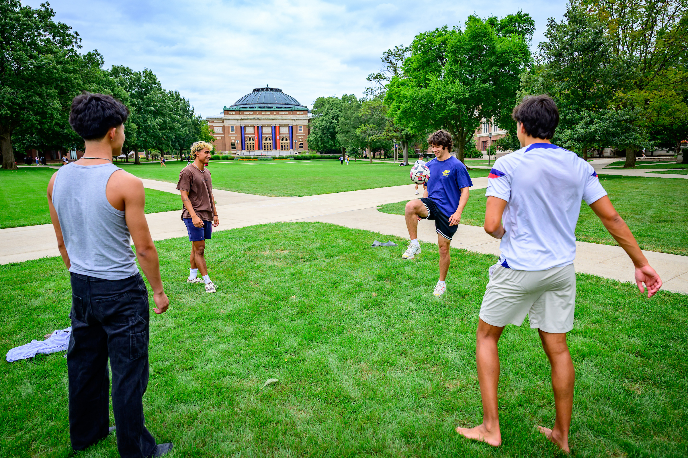 A group of young men play soccer on the Quad during the summer.