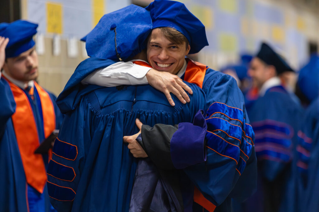 A student hugs a fellow student during graduation